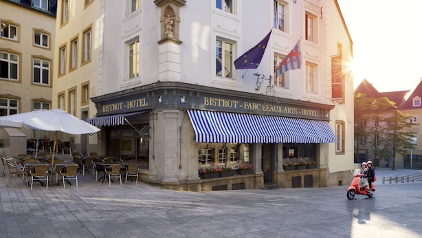 Un hôtel doté d’une terrasse et arborant un drapeau européen.