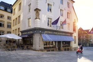 Ein Hotel mit Außenbestuhlung und einer europäischen Flagge.