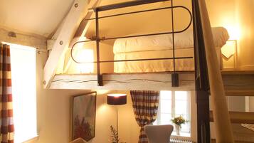 Un dormitorio tipo loft acogedor con una cama litera, un escritorio con silla, un sillón pequeño y un radiador.