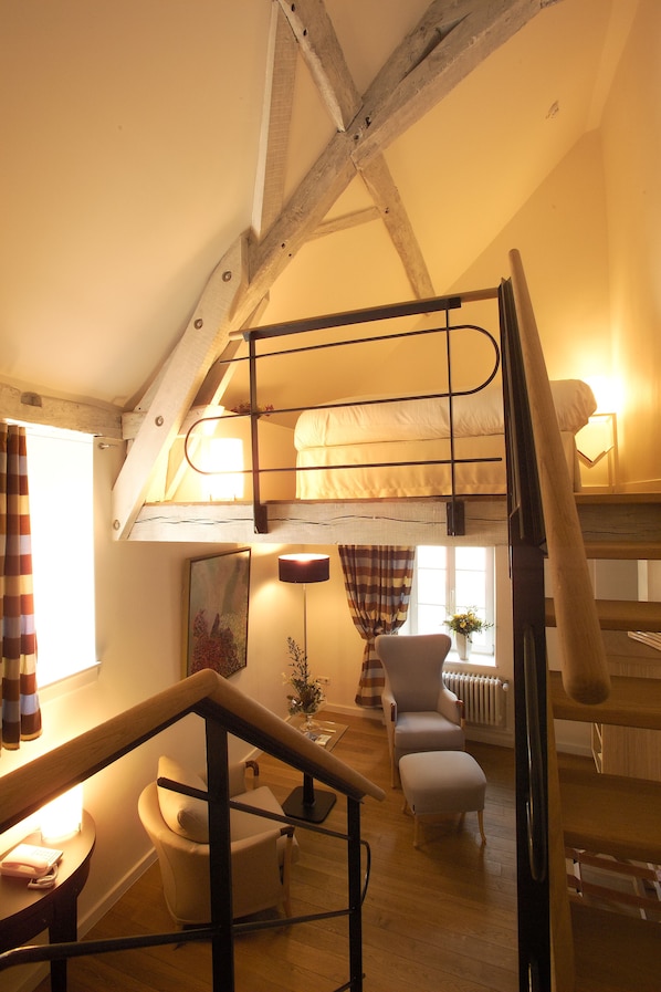 Un dormitorio tipo loft acogedor con una cama litera, un escritorio con silla, un sillón pequeño y un radiador.