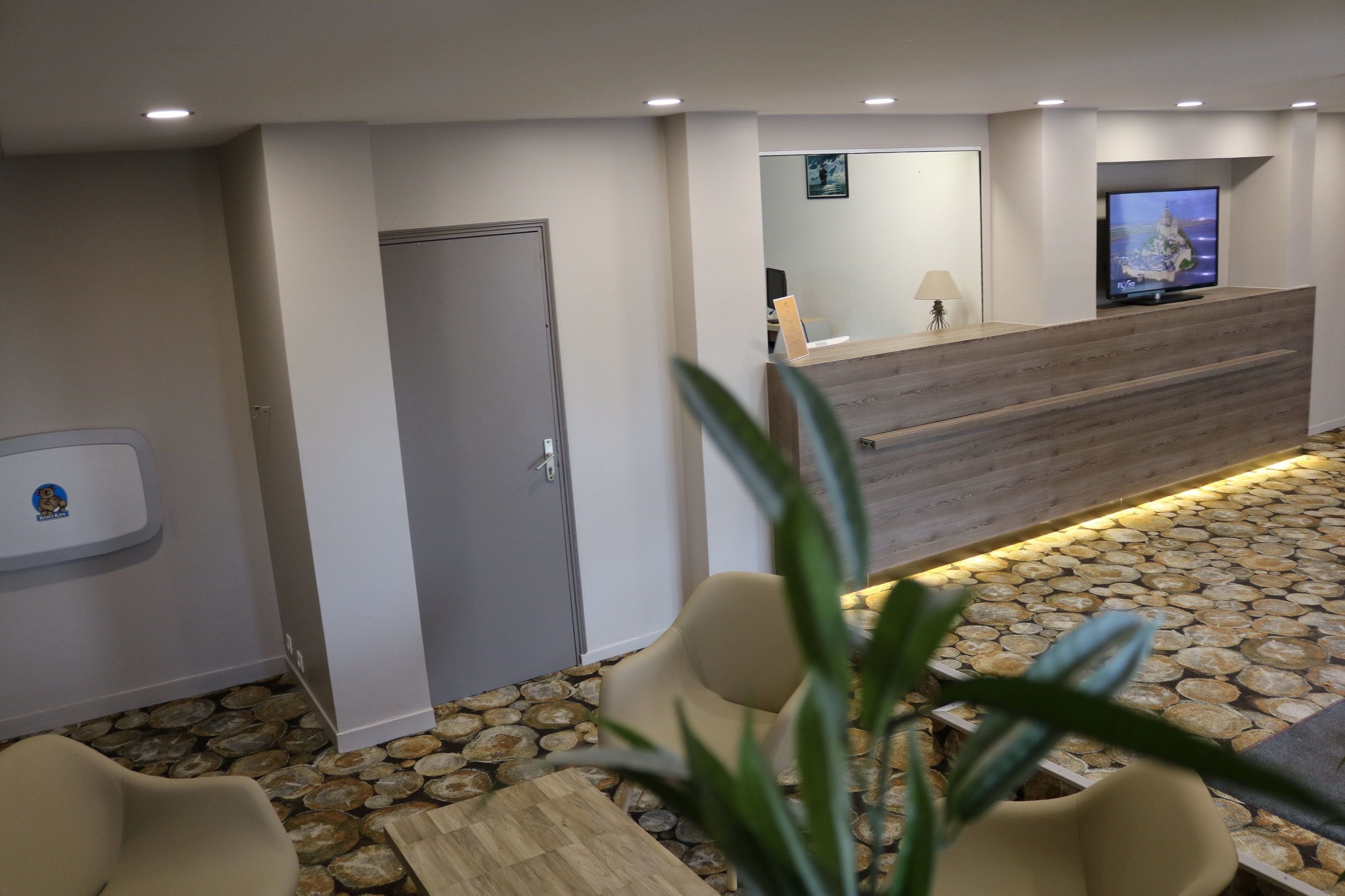 A reception area with a wooden reception desk, a television, and a stone-tiled floor.