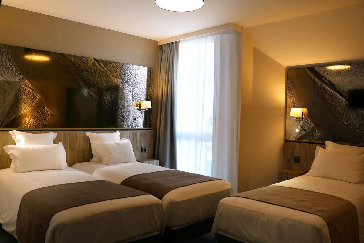 A hotel room with two beds, a large mirror, and a television.
