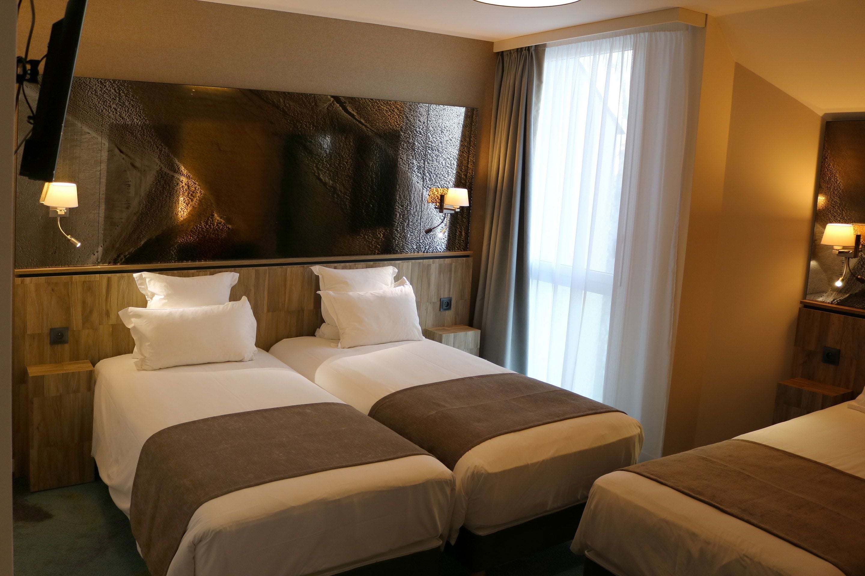A hotel room with two beds, a large mirror, and a view of the outdoors.