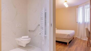 A bathroom with a toilet, shower, and a white towel on the seat.