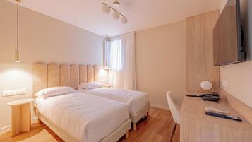 Une chambre d’hôtel avec deux lits, un bureau, une chaise, une télévision et une fenêtre avec des rideaux.