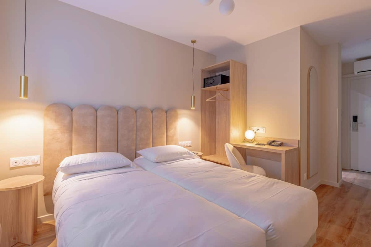 A modern hotel room with a large bed, bedside tables, a desk, and a wardrobe.
