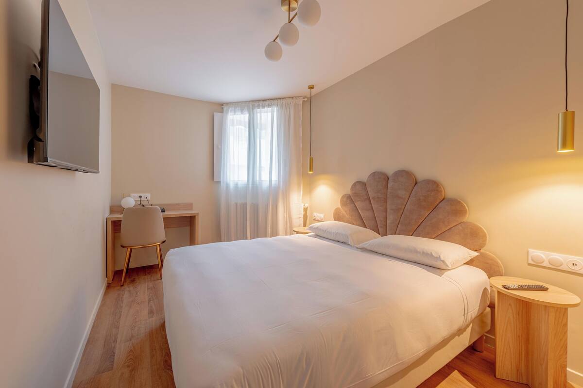 A modern bedroom with a large bed, a desk, and a chair.