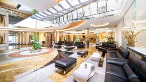 Un hall d’entrée spacieux avec un plafond haut, un mobilier moderne et un arrangement floral central.