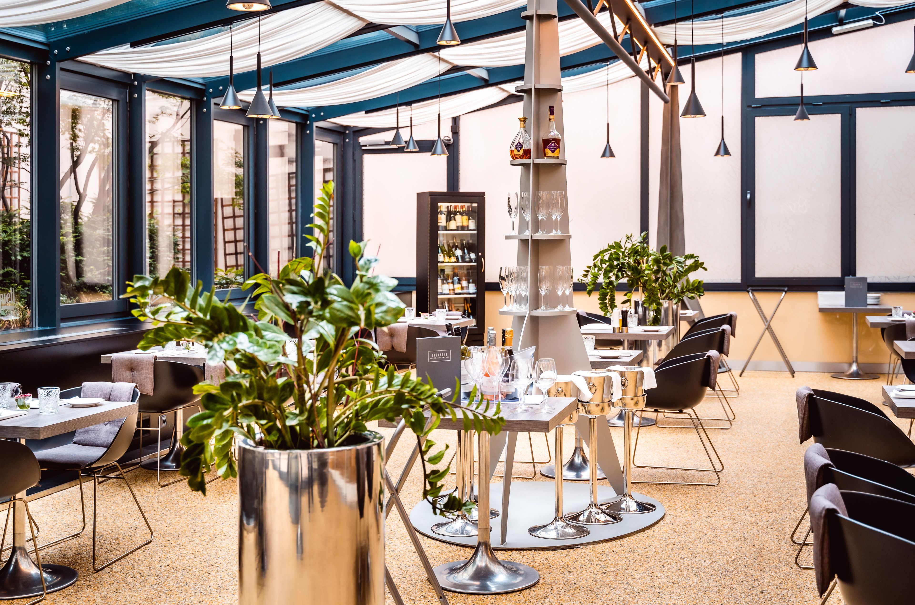 Ein modernes Restaurant mit runden Tischen, Stühlen und einer zentralen Bar.