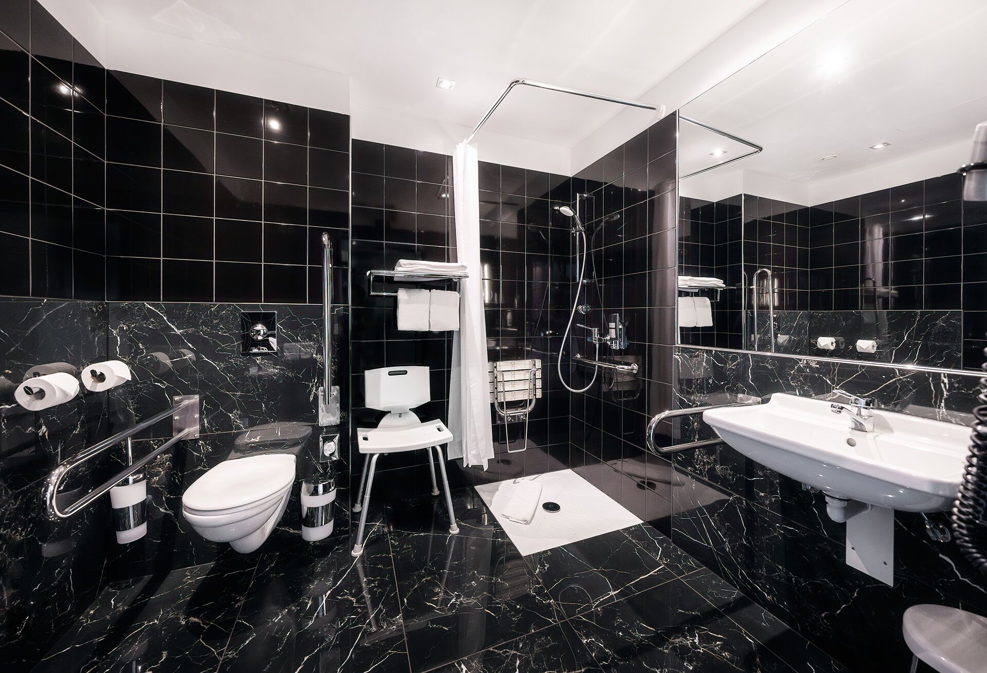 Une salle de bain moderne équipée de toilettes, d’un bidet, d’une douche, d’un grand miroir et d’un lavabo.