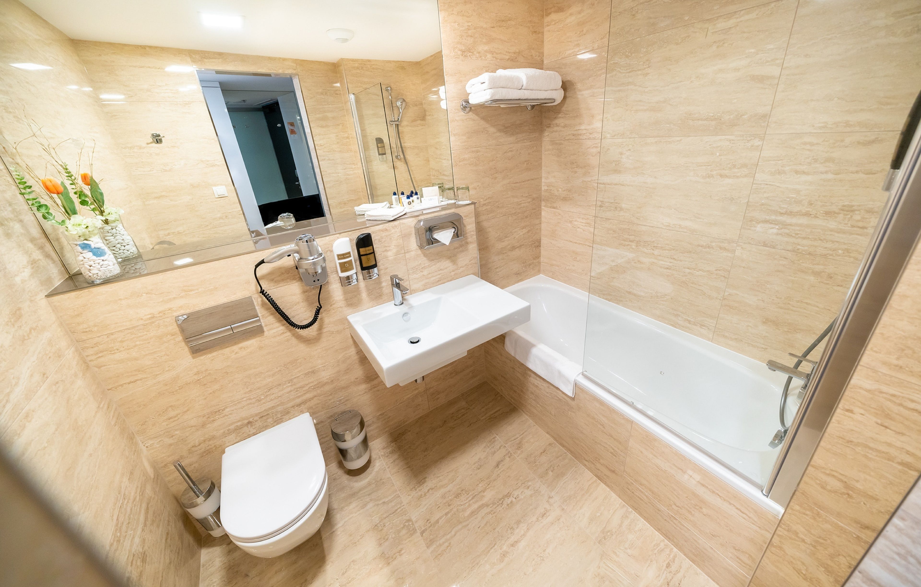 Un baño moderno con ducha de vidrio, lavamanos blanco y retrete.