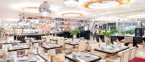 Un comedor moderno con varias mesas y sillas, una barra central y luces decorativas en el techo.