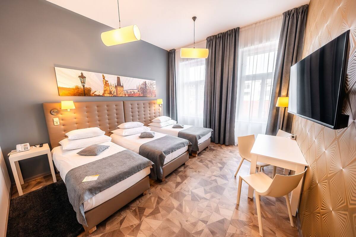 Ein Hotelzimmer mit Bett, Nachttischen, Schreibtisch, Stuhl, Fernseher und einem Bild an der Wand.