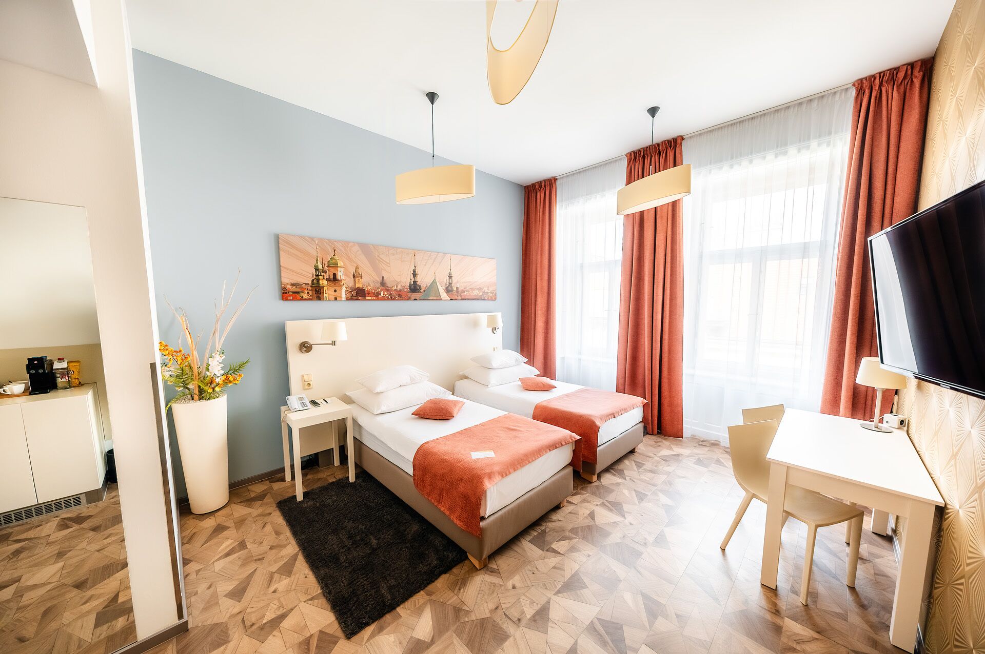 A hotel room with two beds, a desk, a TV, and a painting on the wall.