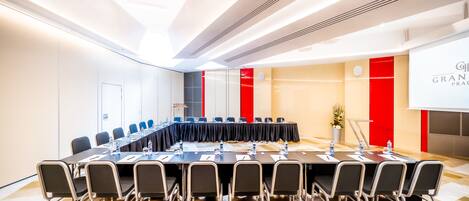 A conference room with a long table, chairs, and a projector screen.