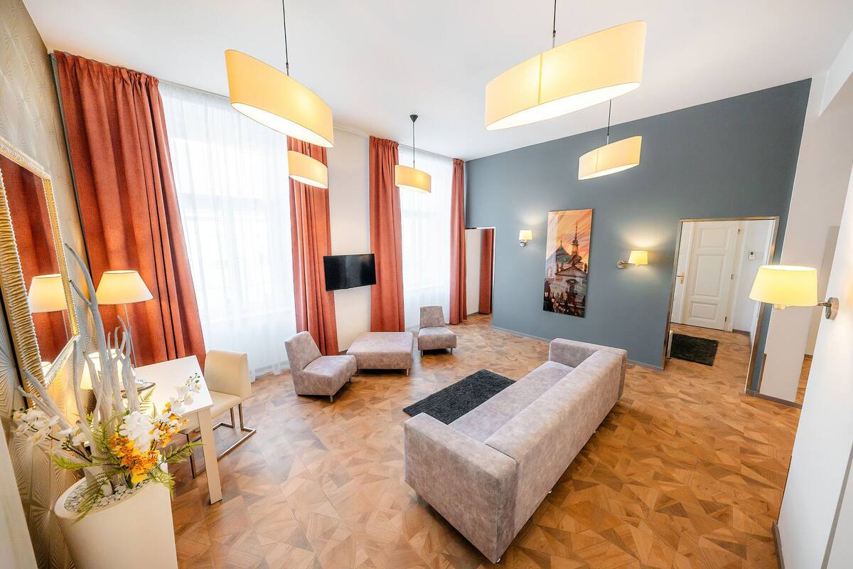 Ein modernes Wohnzimmer mit einer Couch, Sesseln, einem Fernseher und einem Essbereich mit Tisch und Stühlen.