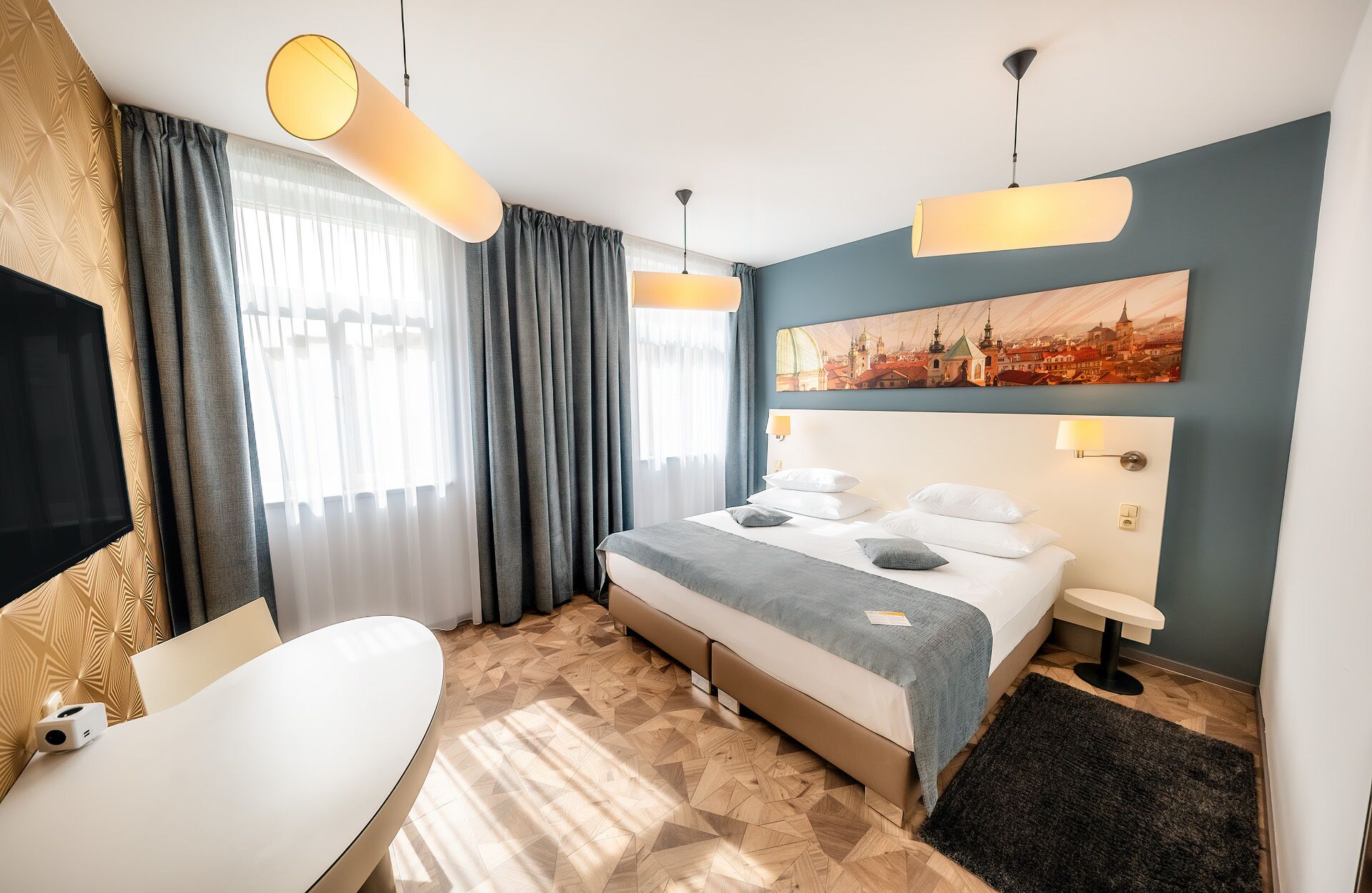 A modern hotel room with a bed, bedside table, lamp, and a painting on the wall.