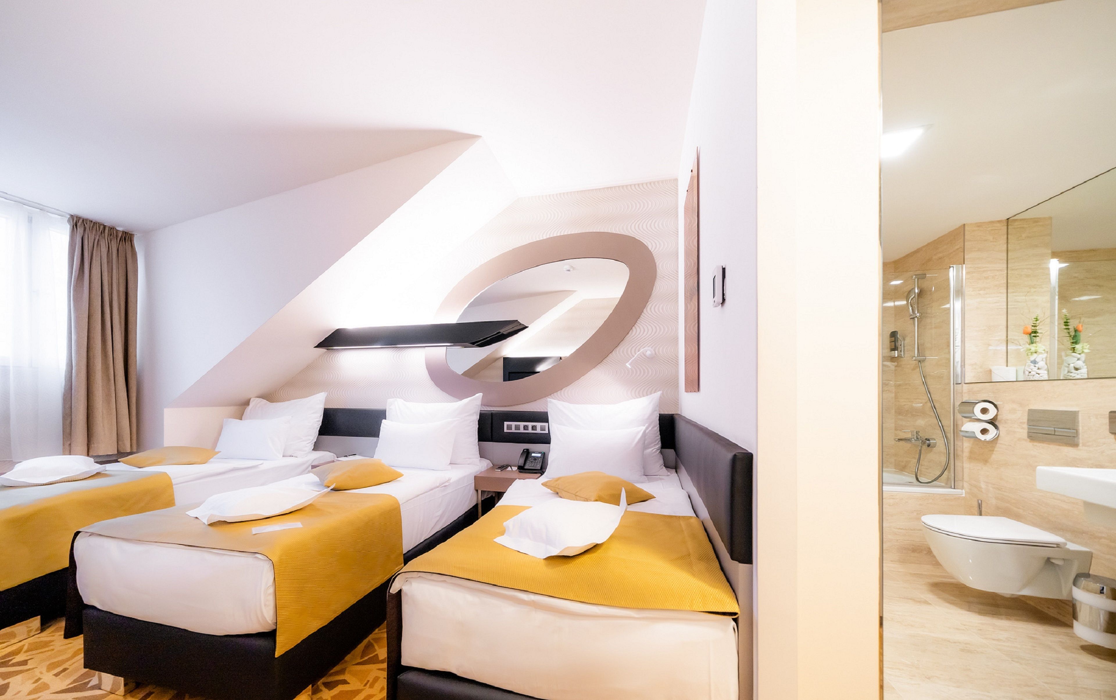 A hotel room with two beds, a large mirror, a shower, and a toilet.