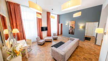 A modern living room with a sofa, armchairs, a flat-screen TV, and a painting on the wall.