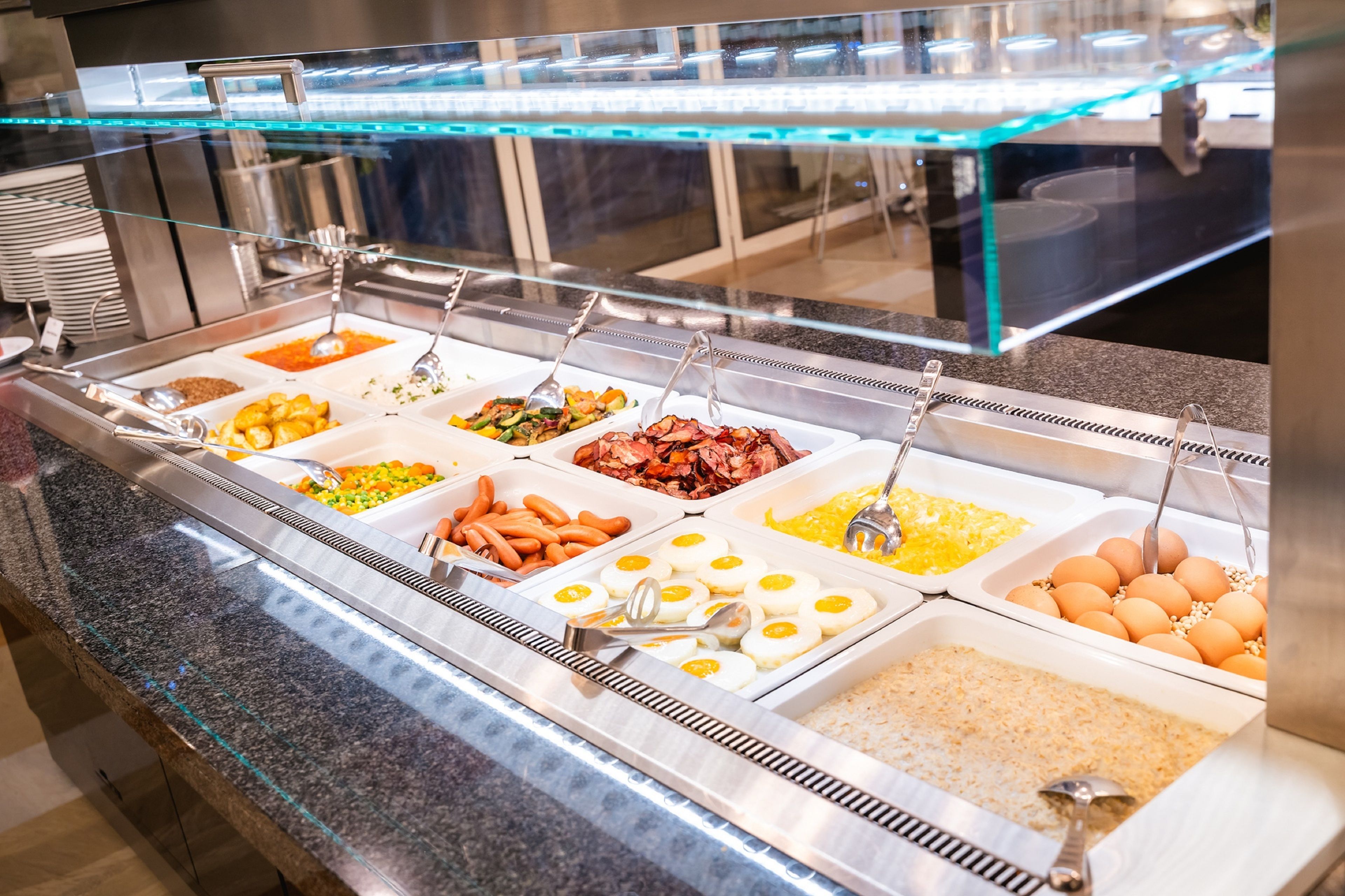 Un buffet proposant une variété de plats, notamment des œufs, des saucisses et du riz.