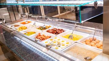 Un buffet proposant une variété de plats, notamment des œufs, des saucisses et du riz.
