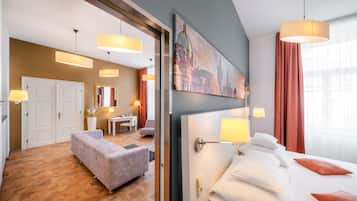 Et hotelværelse med en seng, sengeborde med lamper, et skrivebord, en stol og en sofa.