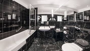 A modern bathroom with a bathtub, a sink, a toilet, and a shower area.