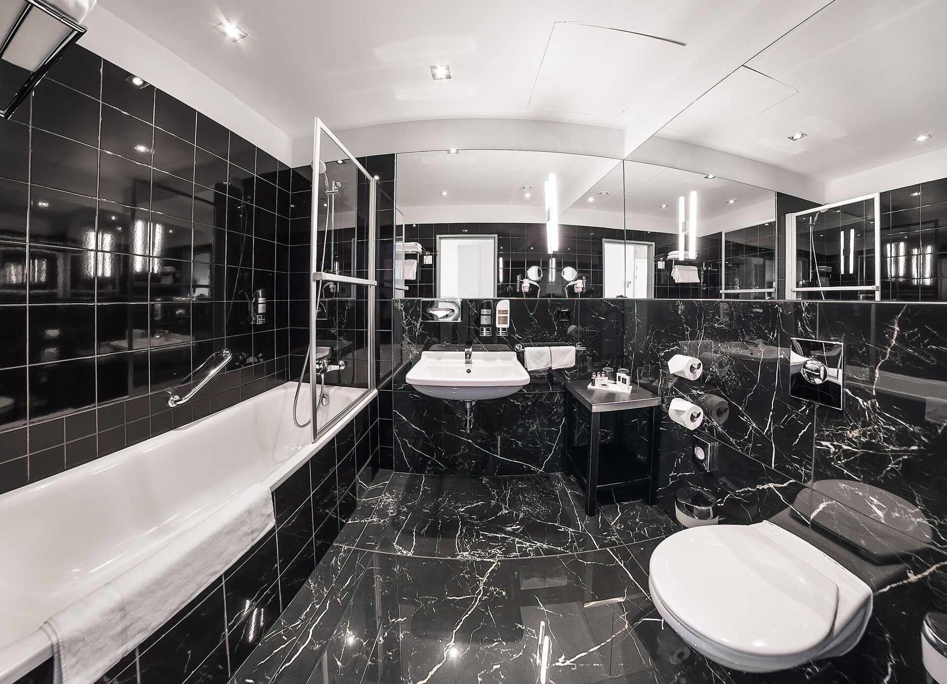 A modern bathroom with a bathtub, a sink, a toilet, and a shower area.