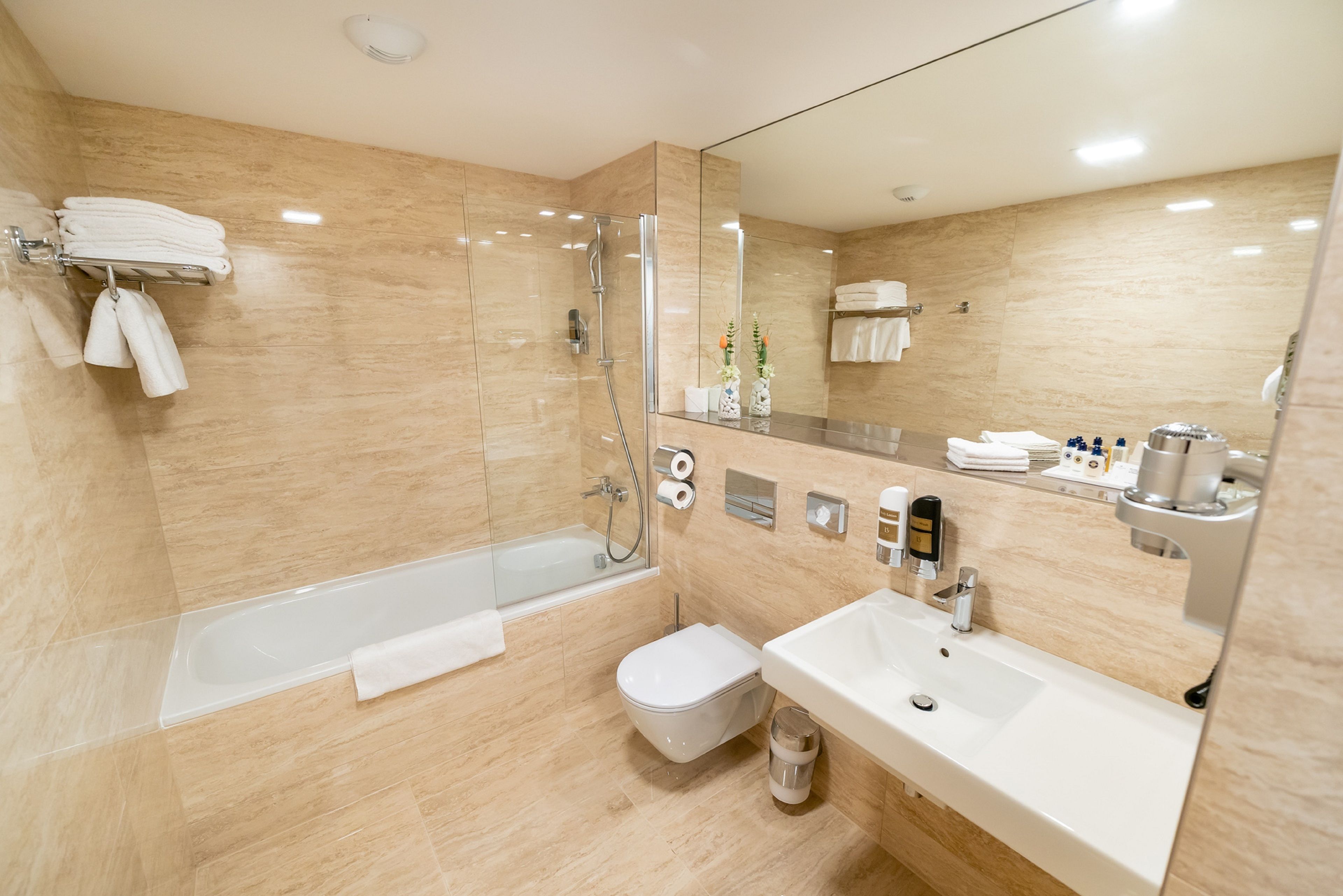 Un baño moderno con ducha envuelta en vidrio, una bañera independiente, un inodoro y un lavamanos con espejo.