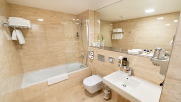 Un baño moderno con ducha envuelta en vidrio, una bañera independiente, un inodoro y un lavamanos con espejo.