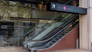 An escalator leading to a hotel entrance with a sign indicating the direction to the hotel. - the b nagoya (Nagoya)
