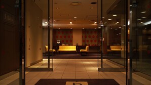 A hotel lobby with a reception desk, seating area, and a 'b' marked entrance mat. - the b nagoya (Nagoya)