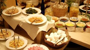 A buffet with various dishes including pasta, salads, and meats, with serving utensils and labels indicating the dishes.