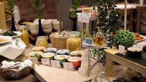 A buffet setup with various food items and condiments, including jars of pickled vegetables, bowls of salad, and a display of bread. - the b nagoya (Nagoya)