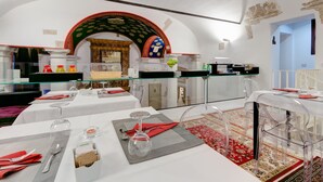 Un comedor con mesas dispuestas para dos, sillas de vidrio transparente y un arco decorativo.