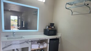 A modern bathroom with a large mirror, a sink, a microwave, and a compact refrigerator. - Townhouse Inn & Suites (Brawley)