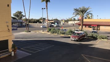 Un estacionamiento con un coche rojo, palmeras y un edificio con un letrero de 'Payday Loans'.