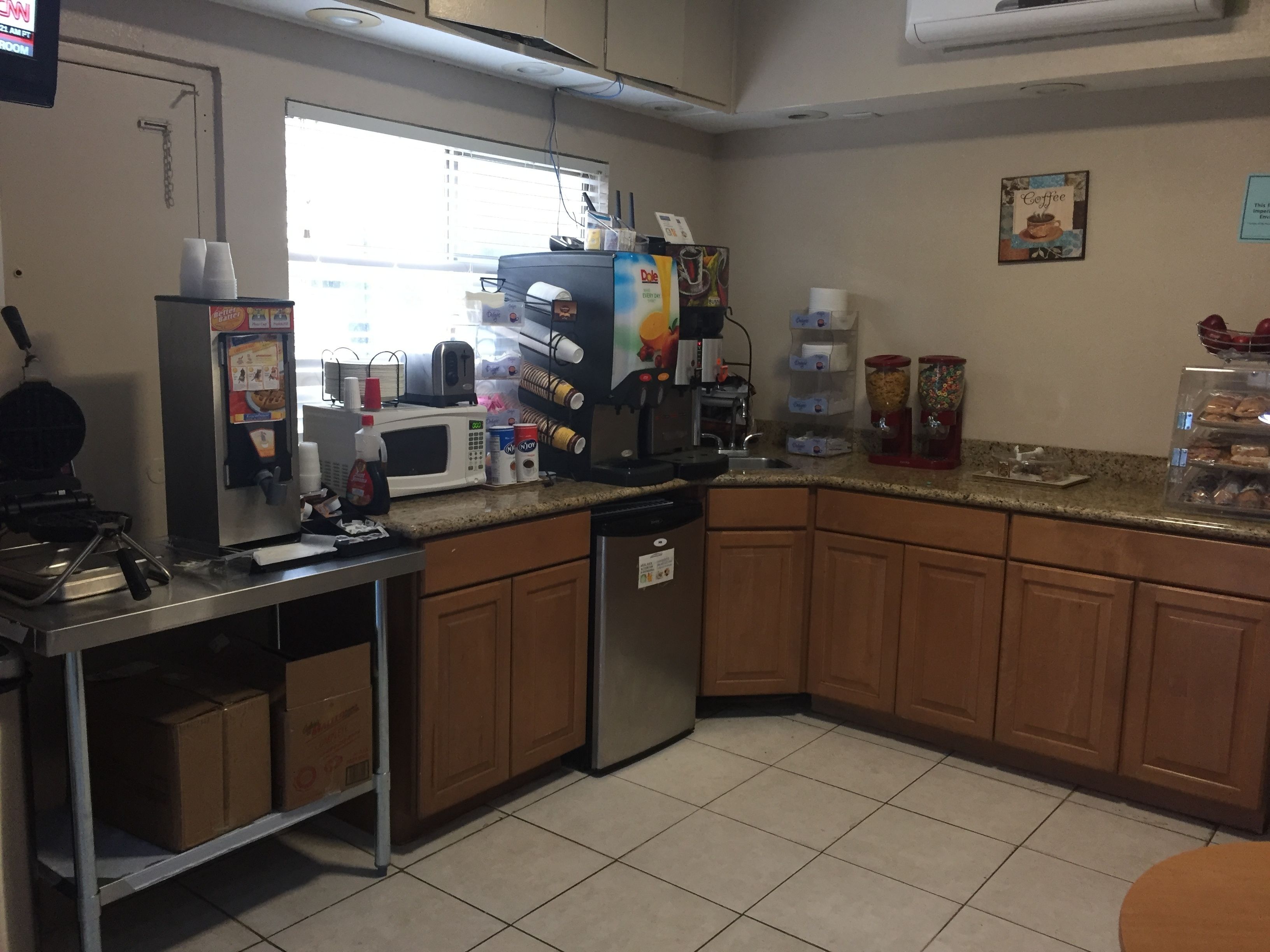 A kitchen with a microwave, coffee maker, and various food items on the counter.