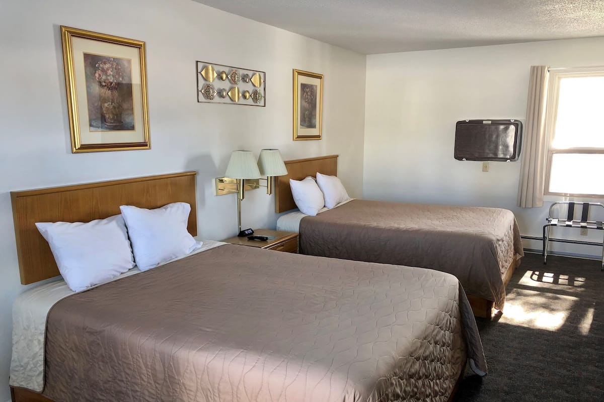 Una habitación de hotel con dos camas, un televisor y una lámpara.