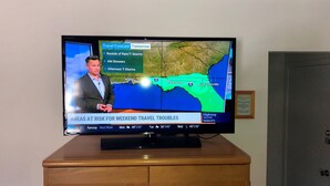 A television displaying a weather forecast with a map of Florida, highlighting areas at risk for travel troubles due to storms.
