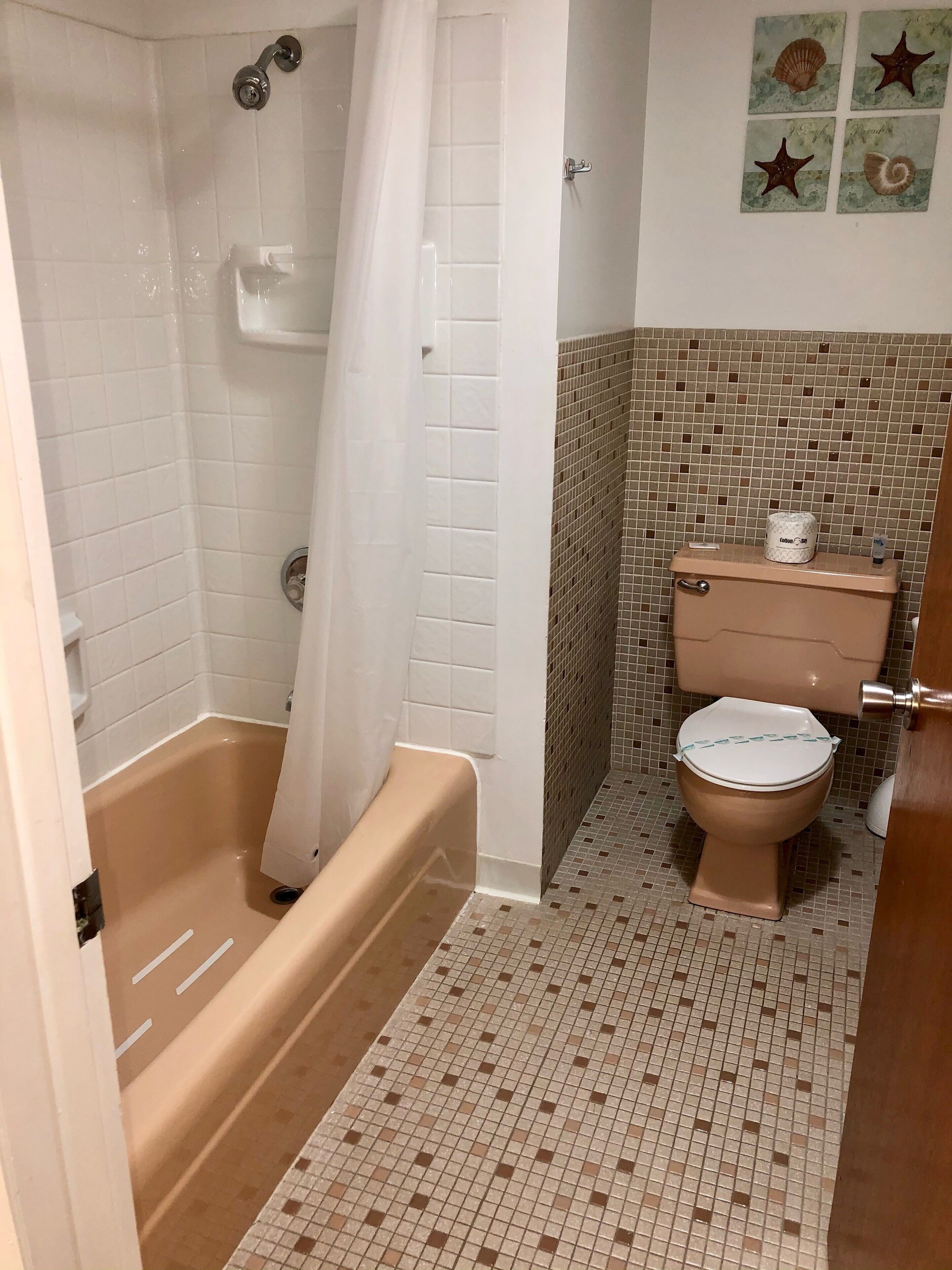A bathroom with a bathtub, toilet, and shower curtain.