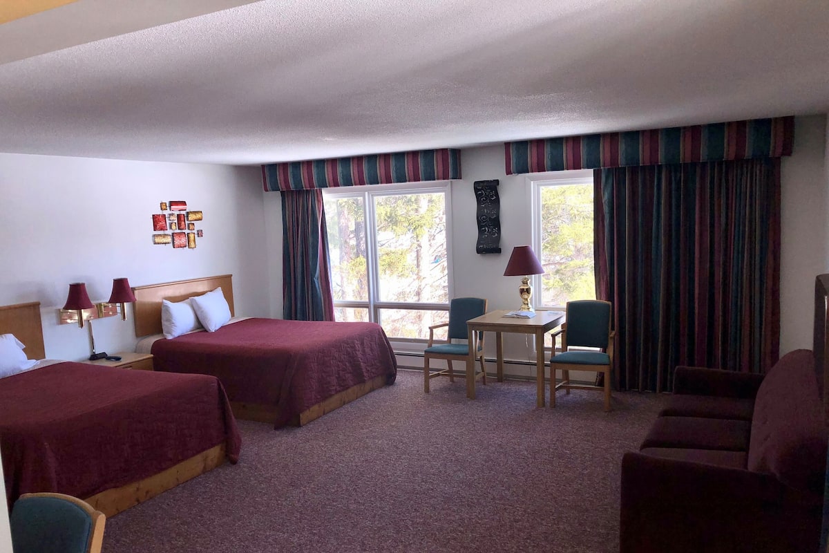 Habitación de hotel con dos camas, un escritorio, una silla y un sofá.