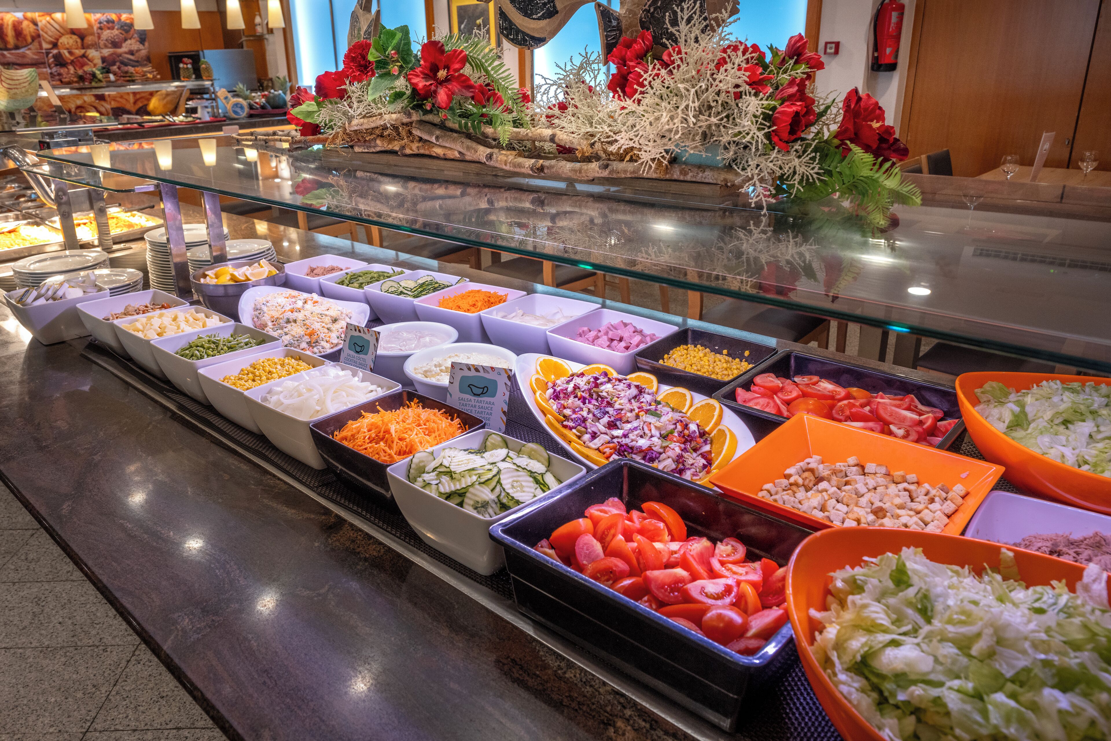 Un bufé con diversas opciones de comida, como ensaladas, verduras y carnes.