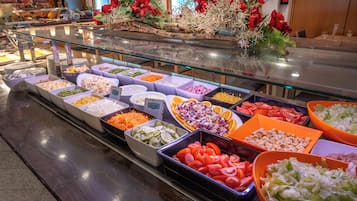 Un bufé con diversas opciones de comida, como ensaladas, verduras y carnes.