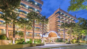 Un hotel moderno de varios pisos, con balcones y una entrada bien iluminada.