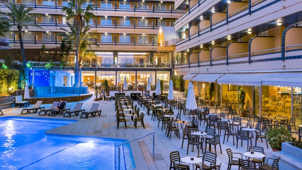 Un hotel con varios balcones, zonas de estar al aire libre y una piscina.