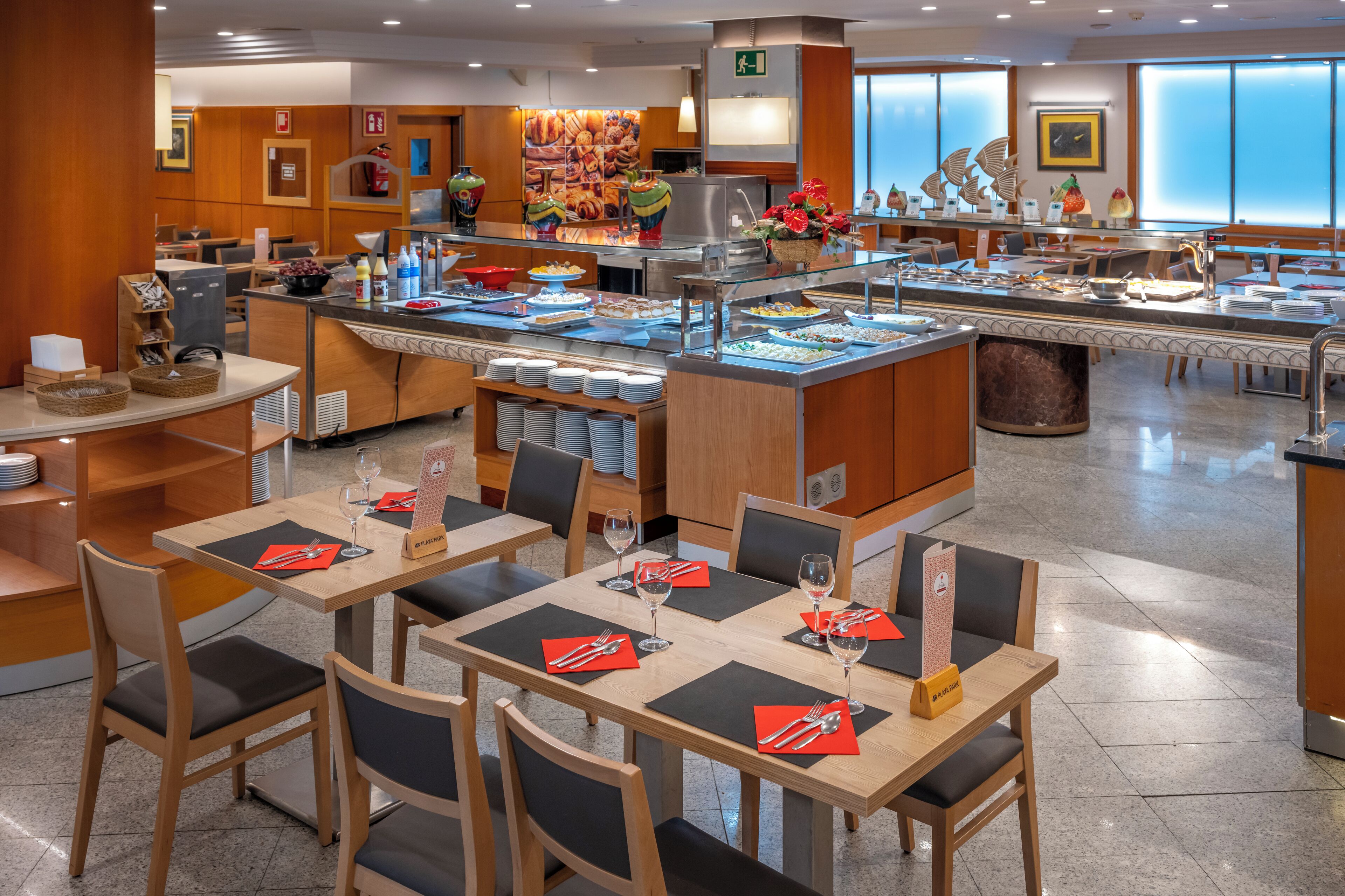 Un comedor de hotel con varias mesas, sillas y una barra de buffet.