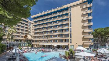 Un hotel con varios balcones, piscina y zonas de estar al aire libre.