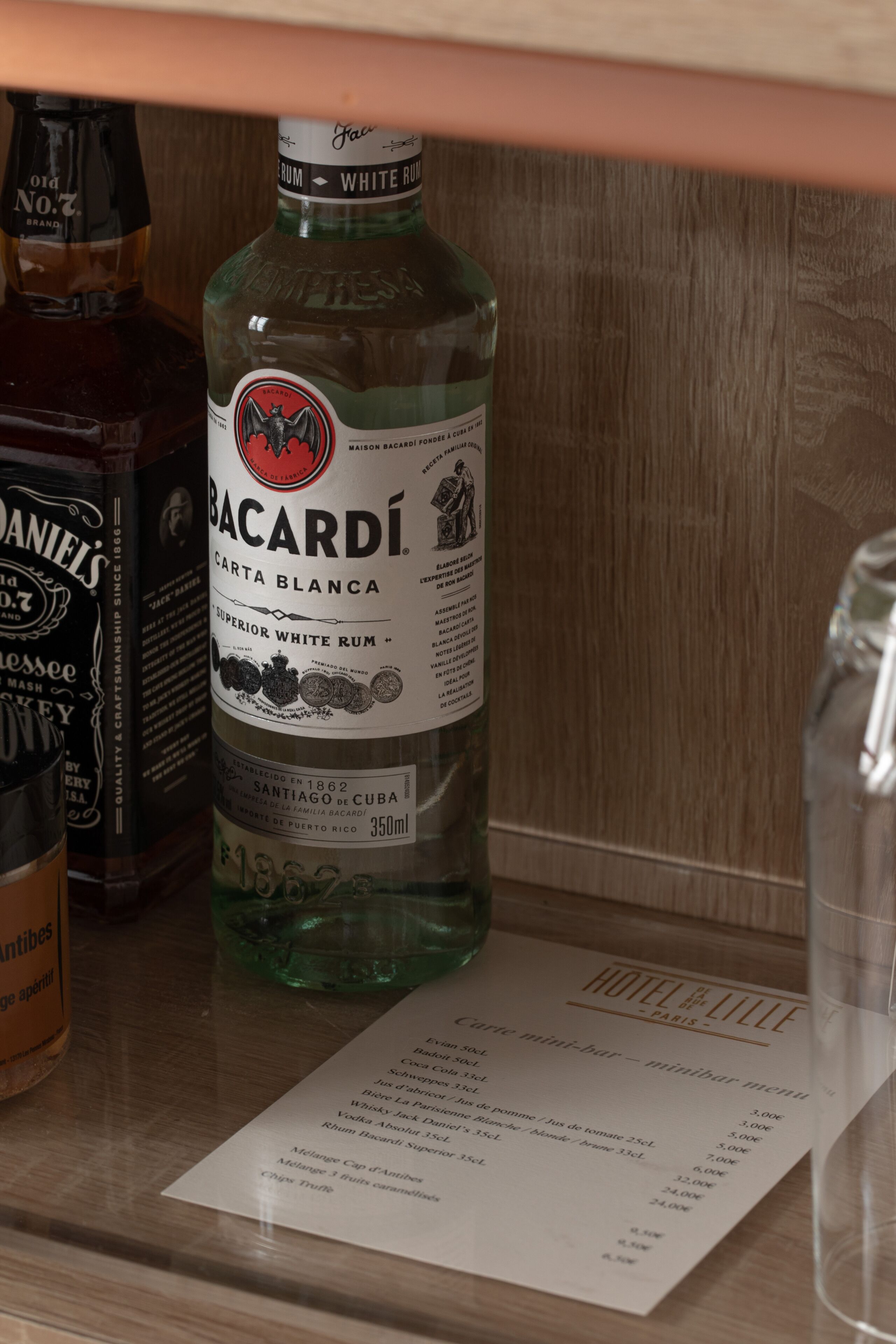 A bottle of Bacardi Carta Blanca on a wooden surface with a menu in front.