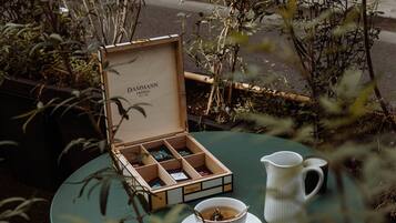 A table with a wooden box, a white pitcher, and a cup, surrounded by greenery.